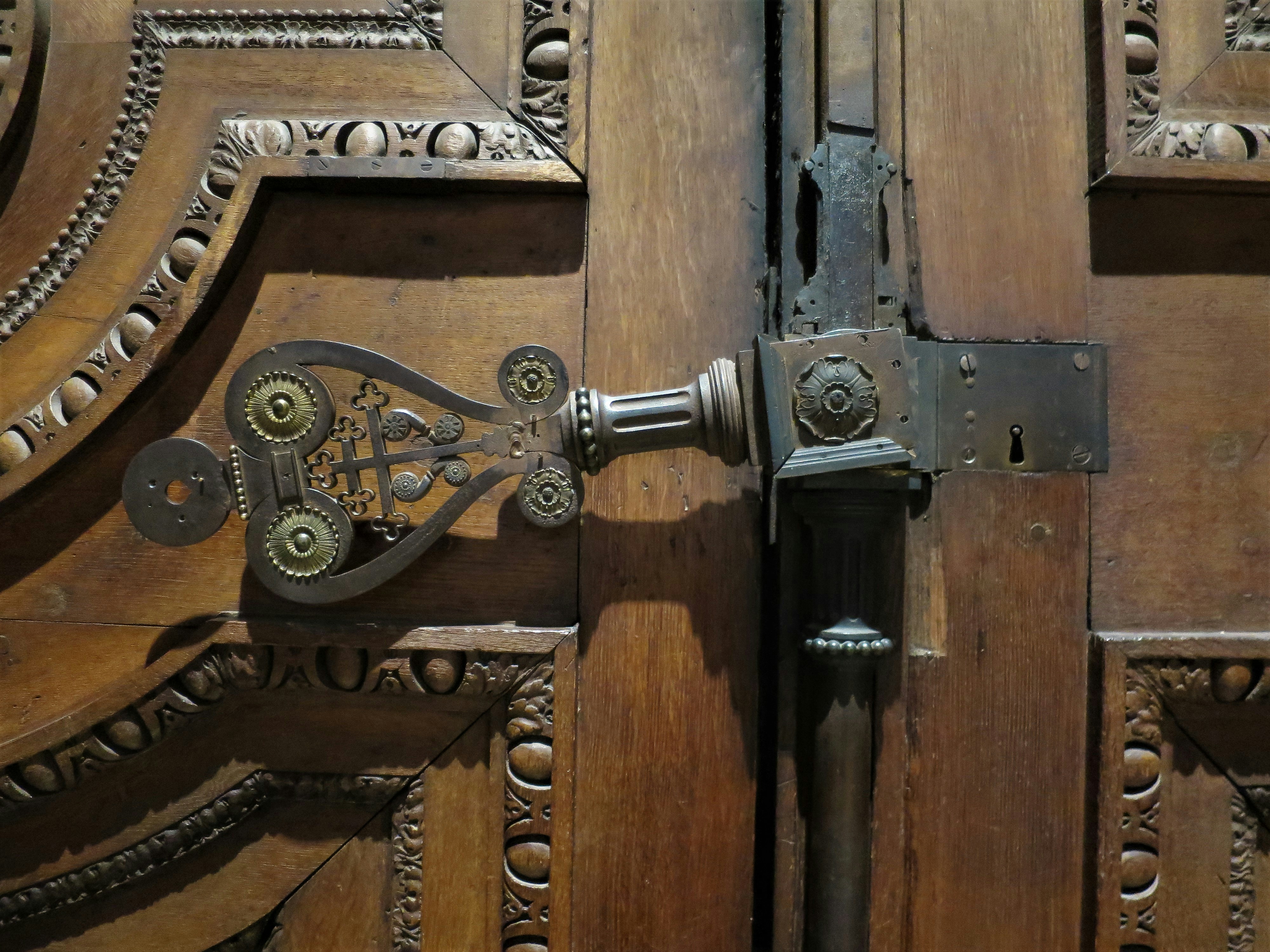 The intricately decorated interior brass door handle on the carved wooden doors of Saint Sulpice Church in Paris, France.